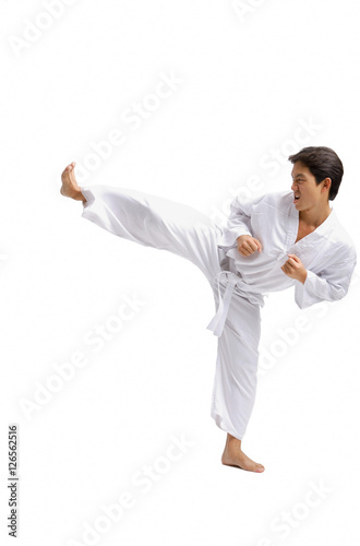 Young man practicing martial arts uniform, kicking with one leg