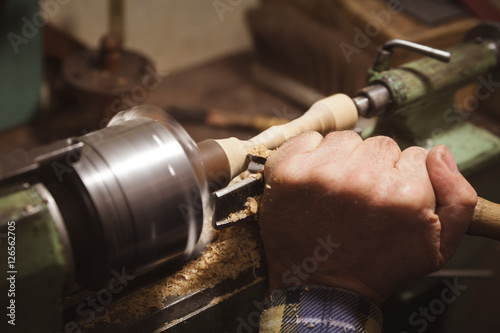 Man makes wood detail on lathe