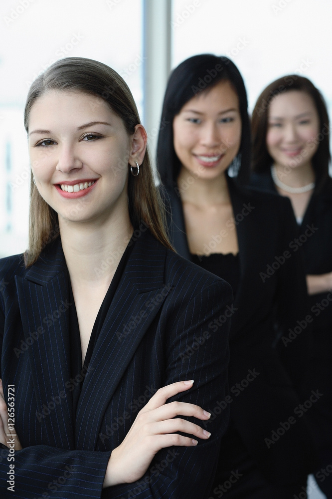 Businesswomen in a row, smiling at camera, Caucasian woman in the front Businesswomen in a row, smiling at camera, Caucasian woman in the front