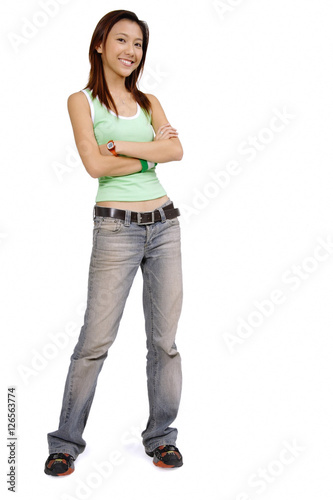Young woman in tank top and jeans, arms crossed, smiling at camera
