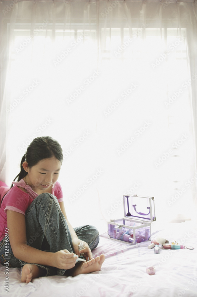 Girl sitting on bed, painting toenails