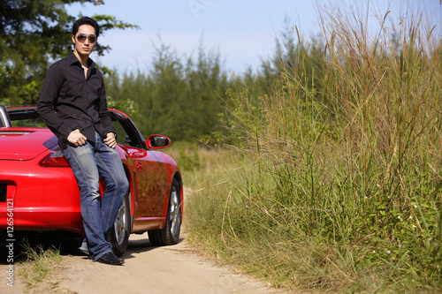 Man leaning on red sports car