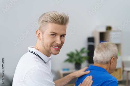 physiotherapeut in seiner praxis mit einem älteren patienten