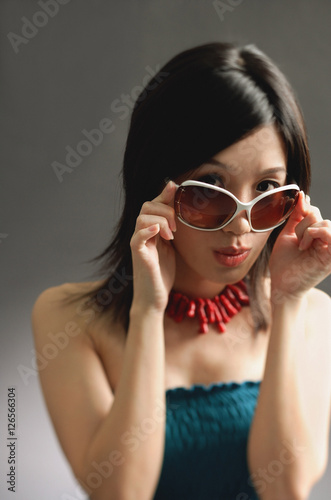 Woman adjusting large sunglasses, looking at camera