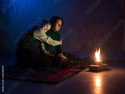 Quadro su tela Adult woman sitting on the floor and crying and the young boy put his head on th