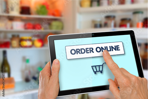 Online Supermarket Shopping Hands with computer tablet shopping cart icon in front of refrigerator