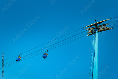 Gondolas ride on a cable across the blue sky