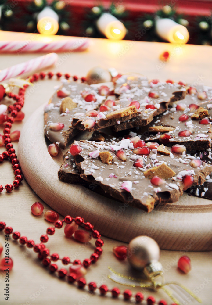 Christmas dessert food idea - festive chocolate with pomegranate seeds, gingerbread cookie and christmas candy cane, selective focus