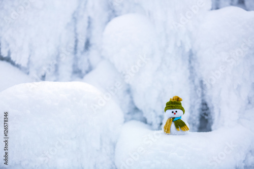 Snowman the Santa's assistant is standing in green hat. photo