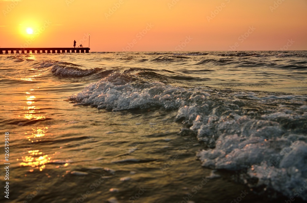 Wave on the calm sea in Italy near by beach with old fisherman during wonderful and colorful summer sunset