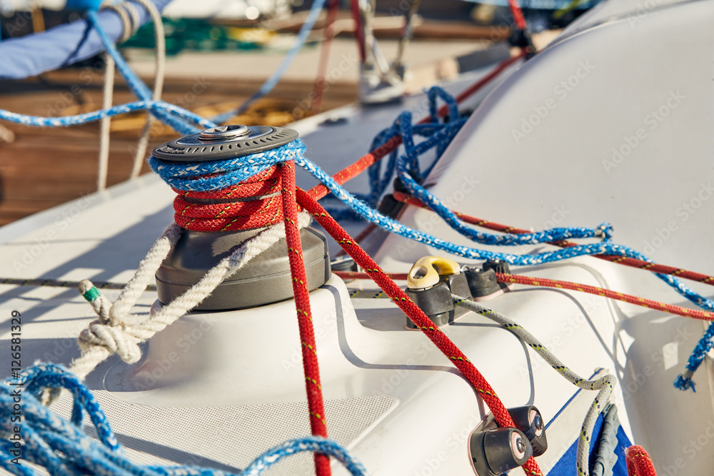 Tangled ropes on the winch on a yacht on background port and blue water Tangled ropes on the winch on a yacht on background port and blue water