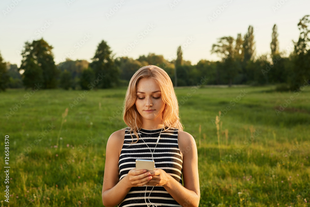 Portrait of fair-haired girl with her mobile phone and earphones Portrait of fair-haired girl with her mobile phone and earphones