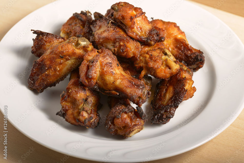 dish of spicy chicken wings on wood dish of spicy chicken wings on wood