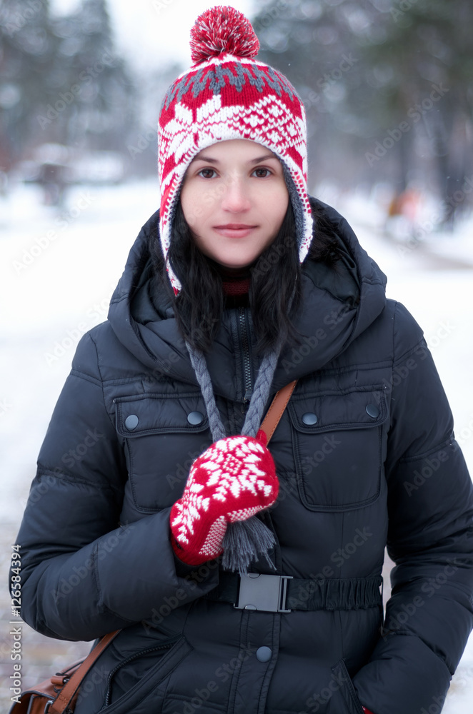 Adorable girl wearing warm clothes outdoors on beautiful winter snow day.Young  Woman having fun in winter park in Snowy Weather.A woman dressed for winter  pulls her drawstrings down and smiles Stock Photo