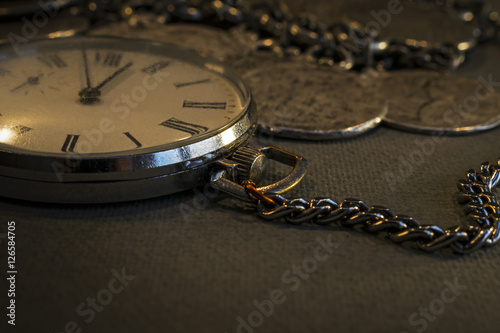 Old pocket watch in dark environment with coin jewelers 