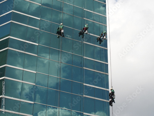 men cleaning glass building by rope access at height