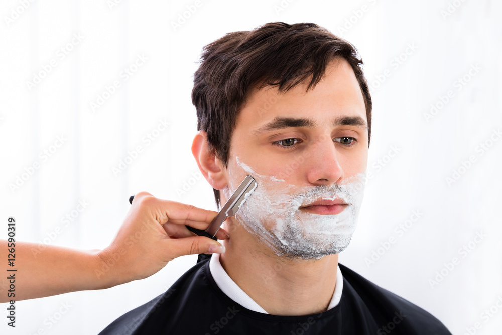 Hairdresser Shaving Man's Beard With Razor