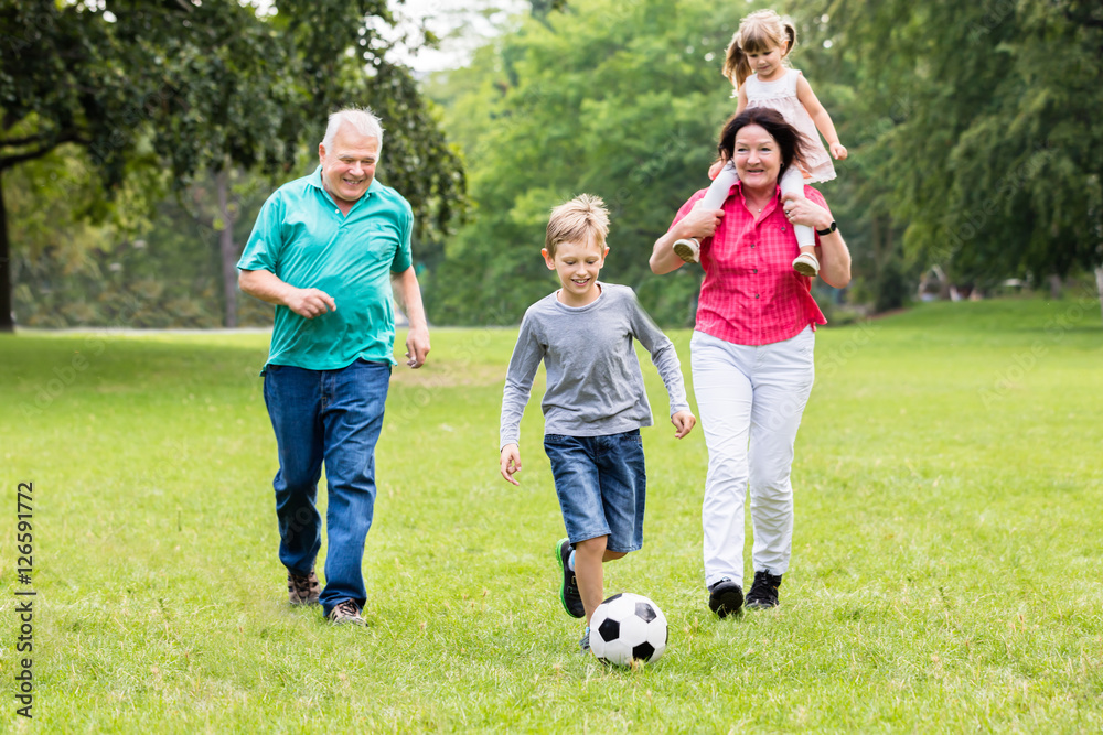 Fototapeta premium Dziadkowie i wnuki grają razem w piłkę nożną