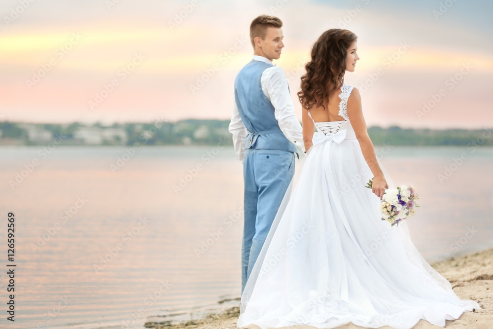 Beautiful wedding couple walking along riverside Beautiful wedding couple walking along riverside