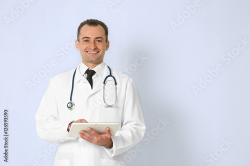 Doctor with tablet on color background