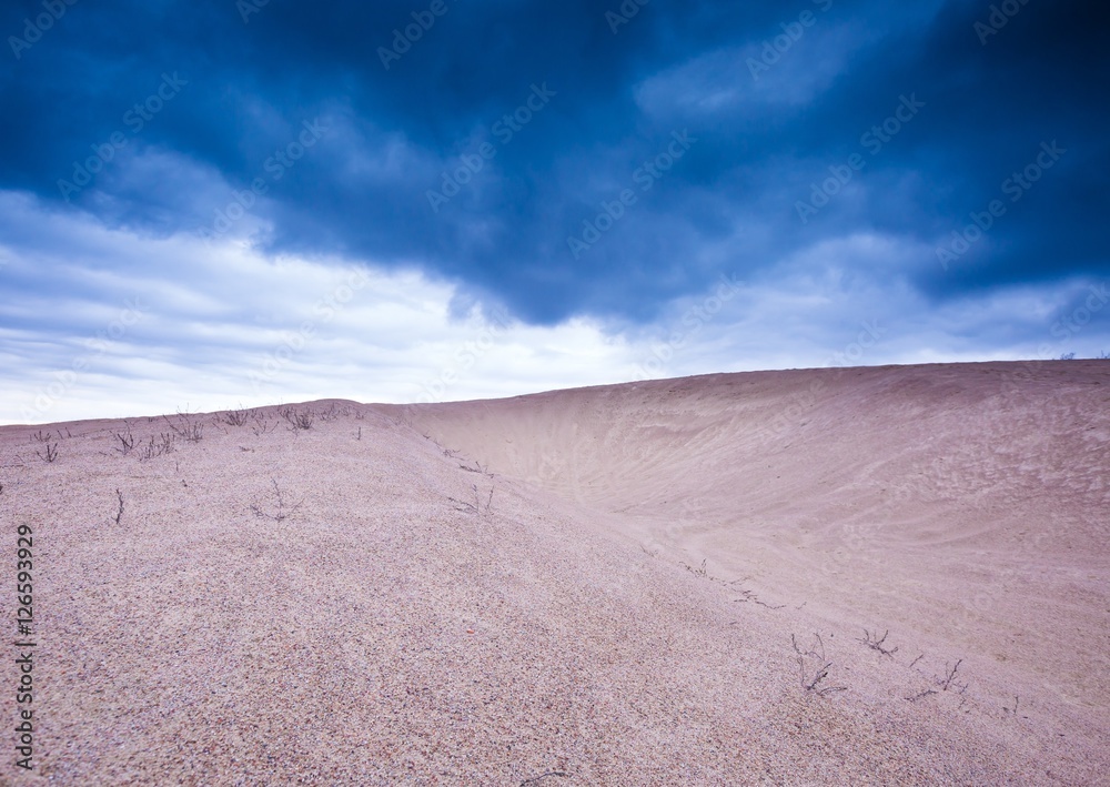 Sand dunes under cloudy sky at evening Sand dunes under cloudy sky at evening