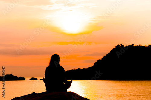 Silhouette, Woman Meditating in Yoga pose or Lotus Position by t