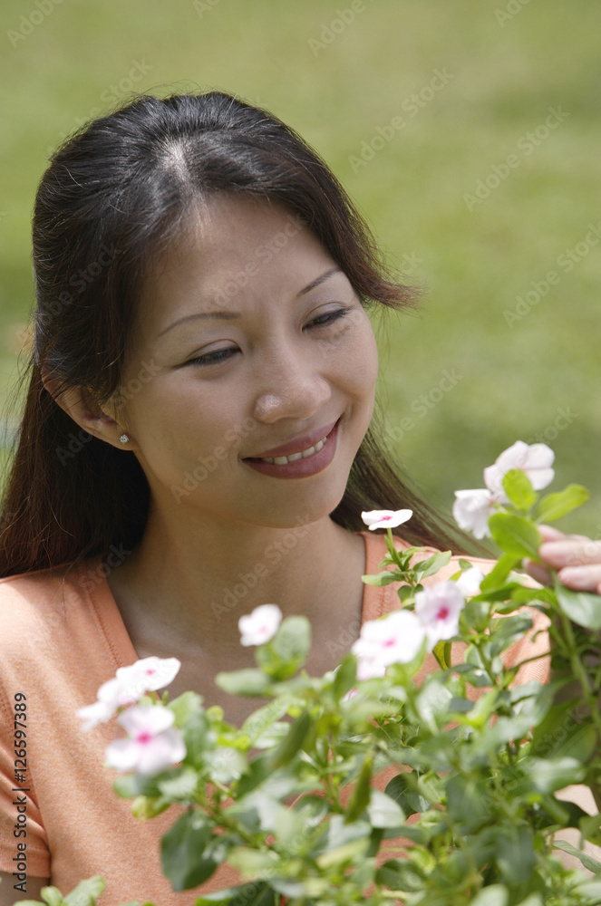Woman outdoors, looking at flowering plants Woman outdoors, looking at flowering plants