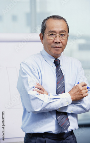 Businessman standing in front of flipchart, arms crossed