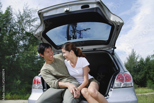 Couple sitting in boot of car