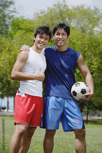 Two men looking at camera, one holding soccer ball