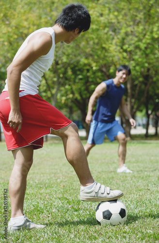 Two men playing soccer in park