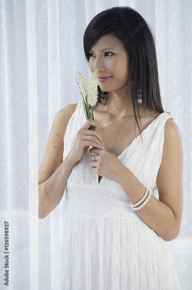woman in white dress holding flowers and smelling flowers woman in white dress holding flowers and smelling flowers