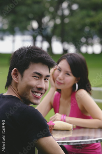 Man turning to smile at camera, woman in the background