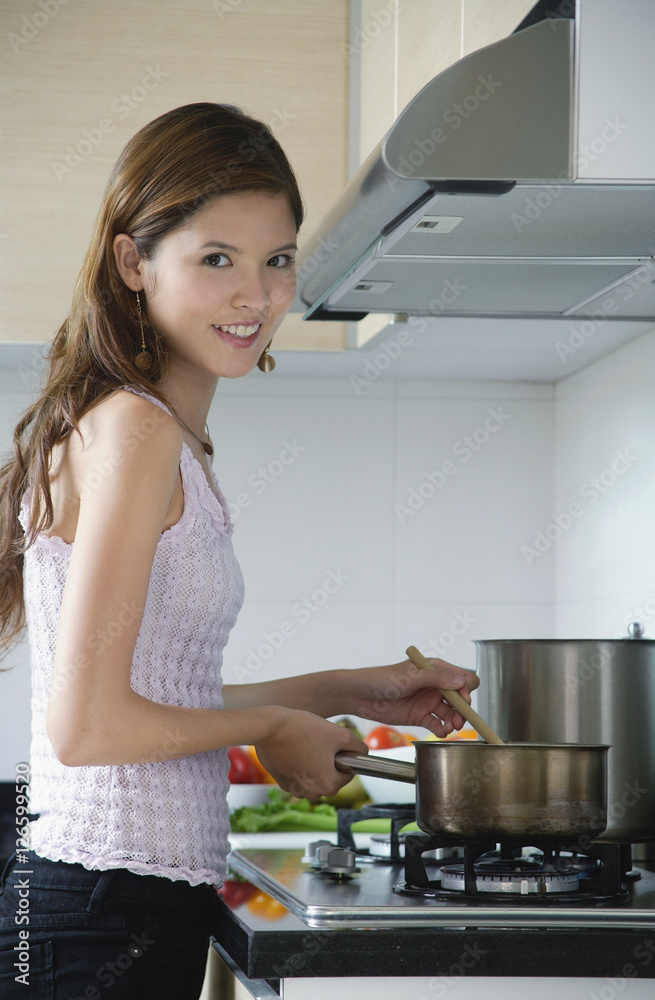 Woman cooking in kitchen, looking at camera