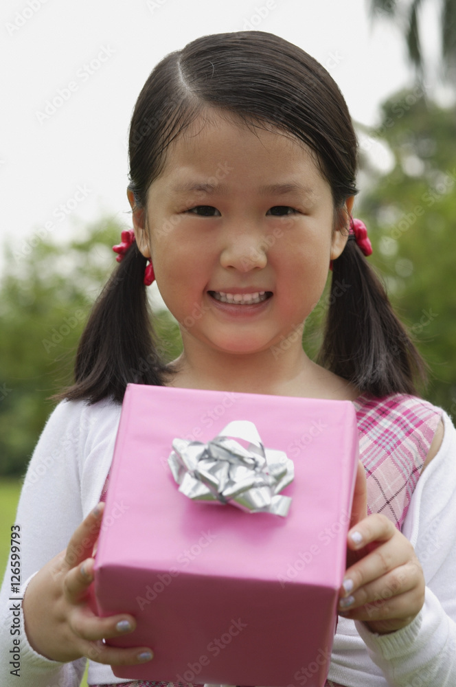 Girl holding pink wrapped gift box, smiling Girl holding pink wrapped gift box, smiling