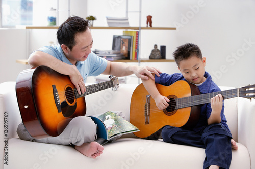 Fotografi Father teaching son to play the guitar