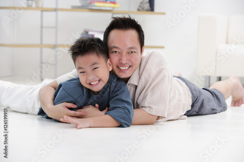 Father and son lying on floor, embracing, portrait