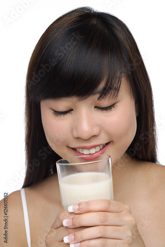Young woman holding glass of milk, eyes closed