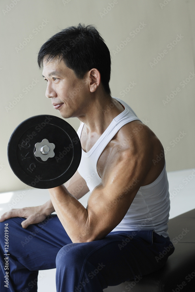 Profile of man lifting arm weights Profile of man lifting arm weights