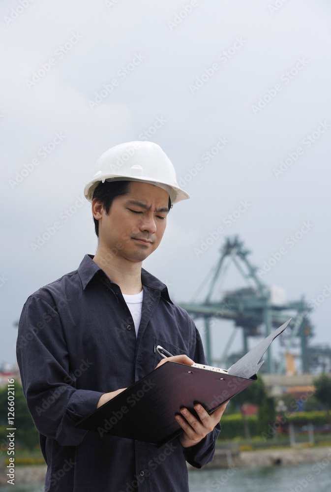 Man with hard helmet writing on clipboard Man with hard helmet writing on clipboard