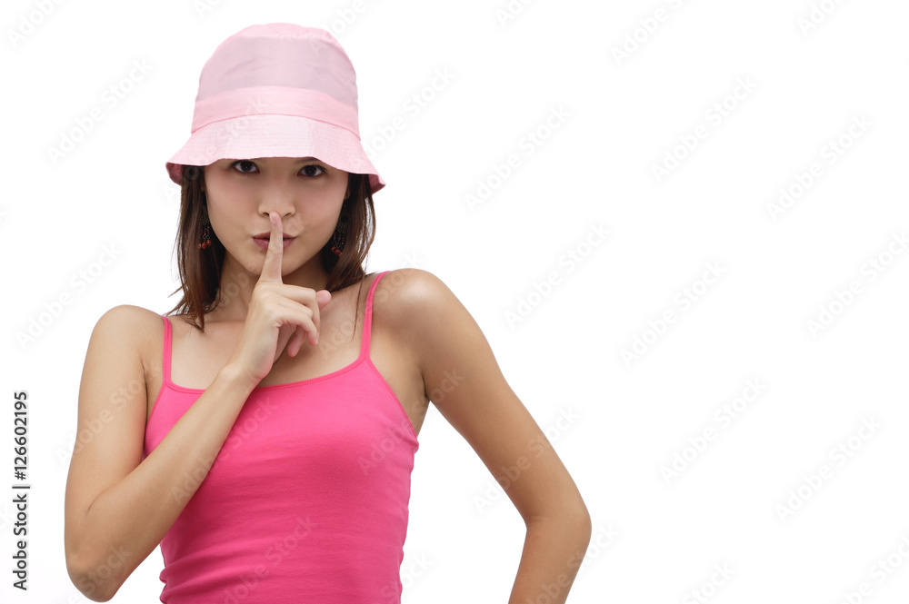 Young woman wearing pink hat with finger to mouth, be quiet please Young woman wearing pink hat with finger to mouth, be quiet please
