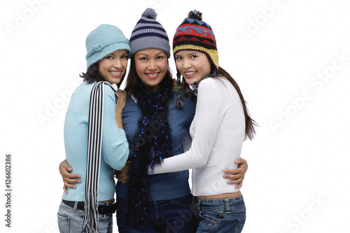 Three women wearing hats and scarves, smiling at camera