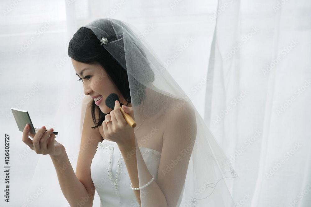 A bride does her makeup in the mirror