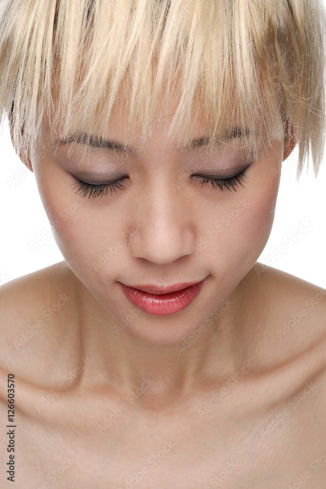 A young woman with dyed blonde hair closes her eyes A young woman with dyed blonde hair closes her eyes