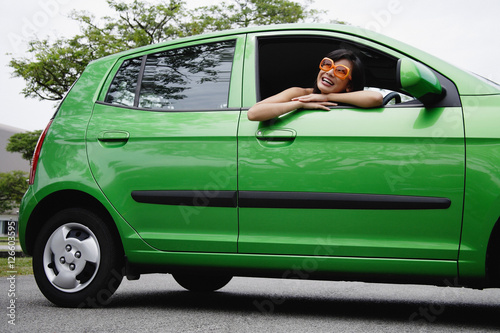 A young woman drives a green car