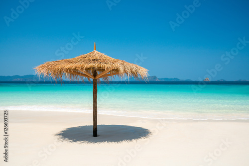 Beach Umbrella made of leafs on white beach in front of Sea day © happystock