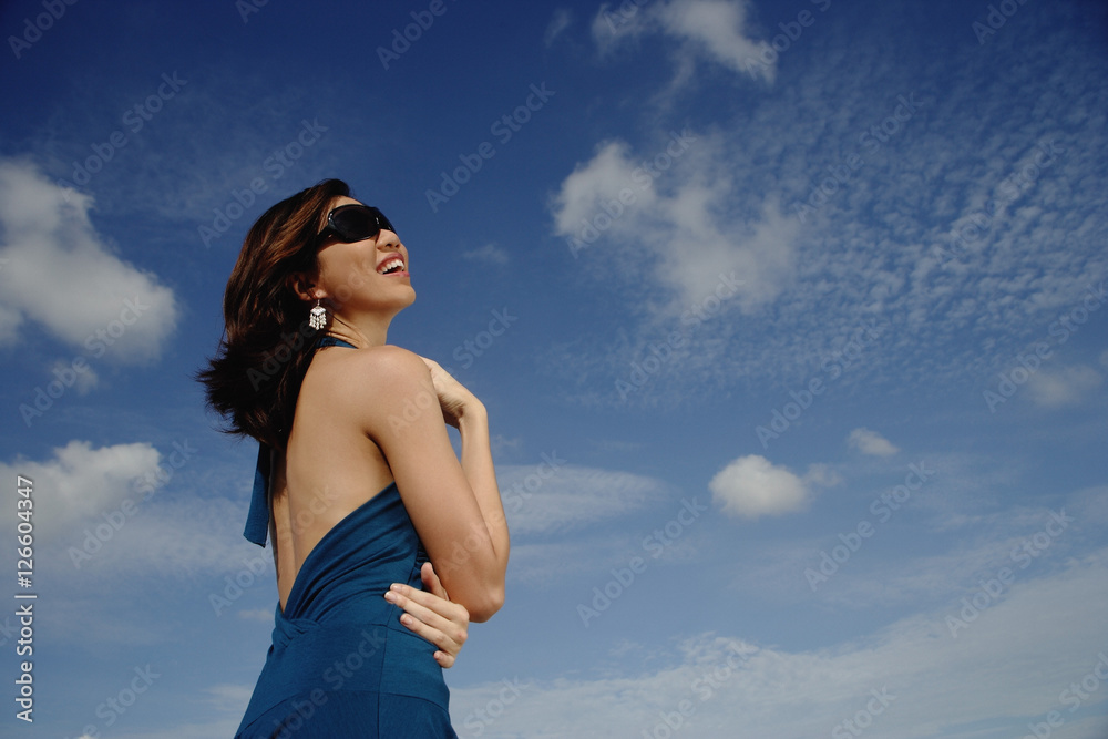 Obraz premium A young woman with sunglasses stands with the sky in the background