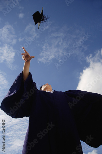 A recent graduate throws his hat in the air in celebration