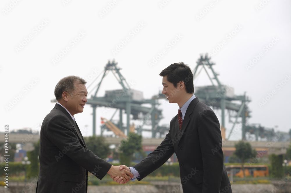 Businessmen standing face to face, shaking hands Businessmen standing face to face, shaking hands