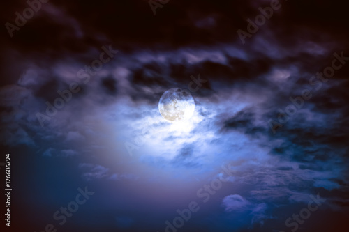 Nighttime sky with clouds and bright full moon with shiny.